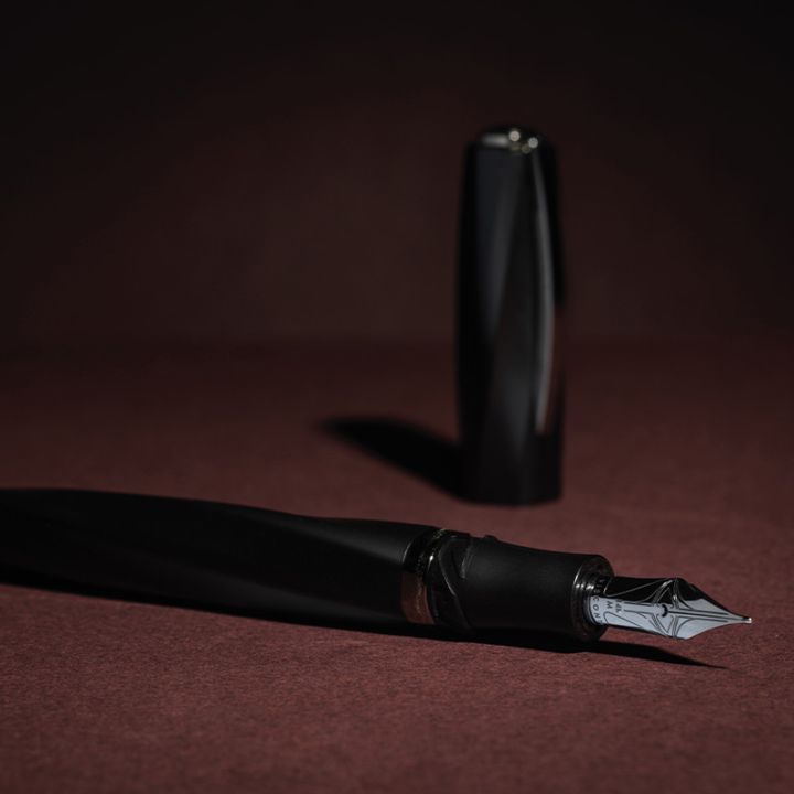A black fountain pen on a burgundy background.