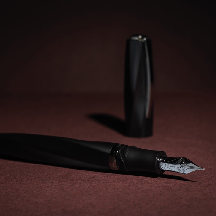 Una penna stilografica nera su sfondo bordeaux.