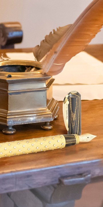 gold and diamond studded King of Diamonds fountain pen in front of antique inkstand