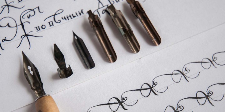 6 different types of calligraphy nibs lined up on paper with rows of practice exercises