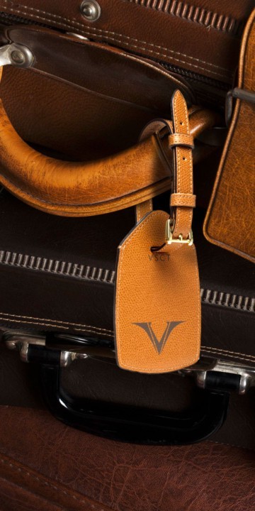 Visconti cognac luggage tag tied around the handle of a suitcase