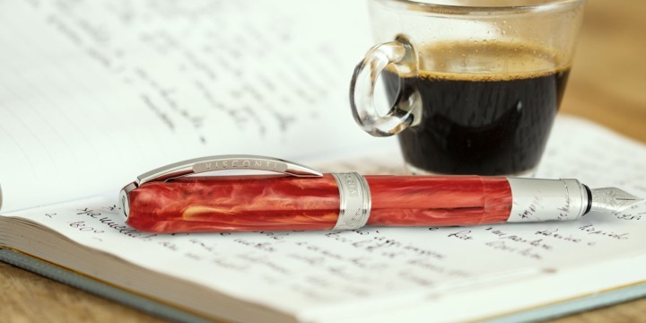 Visconti red Rembrandt pen resting on notebook with coffee cup