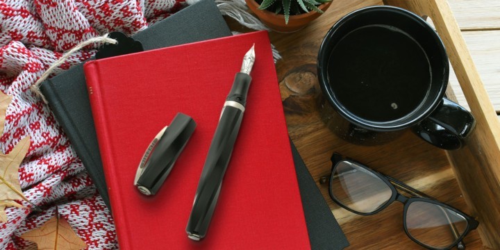 Visconti Divina Matte black fountain pen on red and black books