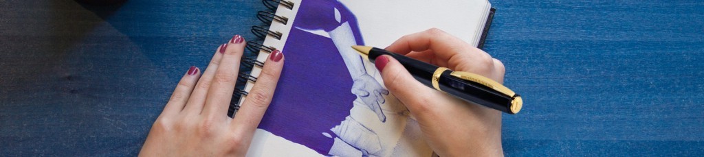 Mano di donna che disegna su un quaderno a spirale con una penna Visconti