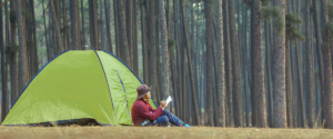Persona che sta scrivendo con la penna stilografica davanti a una tenda da campeggio